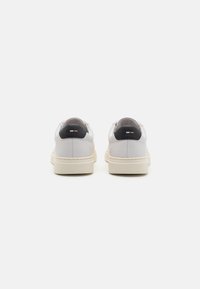 Vita lädersneakers med rund form, kontrasterande mörka hälaccenter och beige gummisulor. Slät yta med minimal sömnad.
