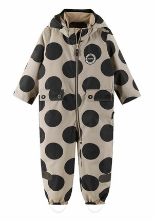 Combinaison de pluie beige pour enfants avec de grands pois noirs, fermeture éclair sur le devant, deux poches poitrine, poignets élastiques et une capuche. Matériau durable et imperméable.