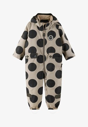 Beige kinderregenpak met grote zwarte stippen, voorrits, twee borstzakken, elastische manchetten en een capuchon. Duurzaam, waterdicht materiaal.