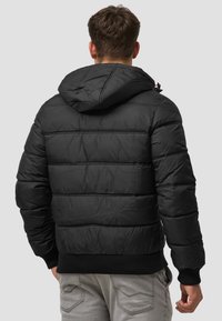 Schwarze Pufferjacke mit Kapuze und gerippten Bündchen. Verfügt über eine gesteppten Textur und eine normale Passform, ideal für Wärme und Komfort.