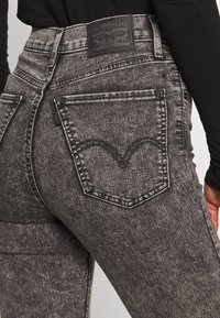 Jeans in denim nero con design di tasche da jeans, caratterizzati da un dettagli cucito curvato e un'etichetta del marchio Levi's in vita.