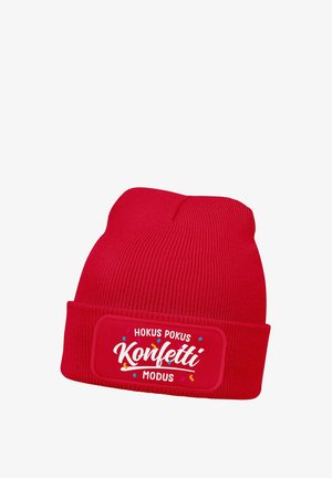 Red knitted beanie with folded cuff featuring white text "Hokus Pokus Konfetti Modus" surrounded by colorful confetti graphics.