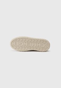 Sneaker sole in light beige rubber, featuring a textured outsole with star patterns and embossed branding in the center.