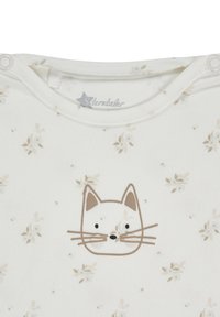 White cotton bodysuit featuring a printed cat face in brown and black, with small floral patterns in soft beige across the fabric.