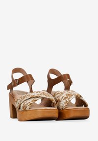 Brown leather wedge sandals with a woven straw front, featuring an ankle strap with buckle, and a wood-like heel for stability.