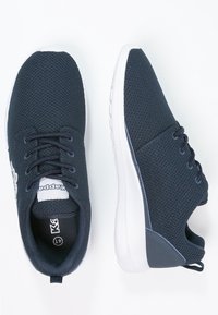 Mörkblå träningsskor med övre del i mesh, vit gummisula, sex hylsor för skosnören och en logotypmärke på tungan.