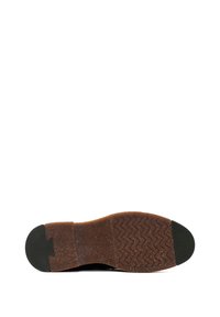 Semelle d'une chaussure marron avec un talon et des coussinets en caoutchouc texturé, et un motif de crampons en zigzag sur la zone avant.