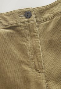 Khakifarbener Cordstoff mit vertikalen Rippen, ausgestattet mit einem dunklen Knopfverschluss, flachem Vorderteil und seitlichen Taschennahtdetails.