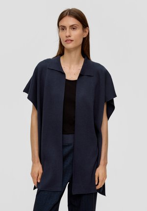 Navy open-front kledingstuk met een kraag, korte mouwen en een relaxte pasvorm, gemaakt van een gestructureerde stof, gecombineerd met een zwarte top en blauwe broek.