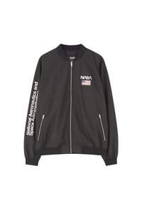 Giacca bomber nera con logo NASA e patch con la bandiera americana, dotata di chiusura con zip, tasche laterali e testo sulla manica sinistra.