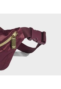 Burgundy fanny pack made of lightweight material, featuring a gold zipper, adjustable strap, and smooth texture with subtle stitching detail.