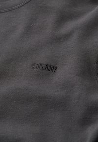 Felpa grigia in tessuto morbido, con collo a giro coste e discreto logo "SUPERDRY" ricamato sul davanti.