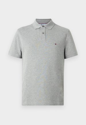 Polo gris de manga corta con dos botones y un pequeño logo rectangular en rojo, blanco y azul en el lado izquierdo del pecho.