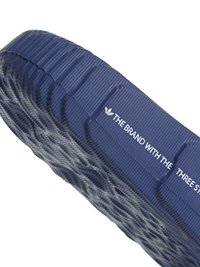 Modra gumijasta sandal s podplatom z vidno teksturo, valovitim vzorcem na podplatu ter belim značilnim napisom ob strani.