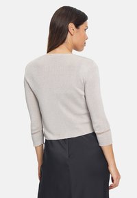 Világosszürke, rövid ujjú felső, textúrált felülettel. Kerek nyakú, és finom nyitott mintákkal díszített ujjak.