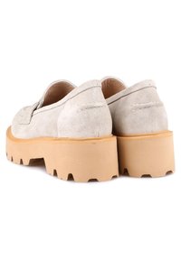 Chaussures en daim beige avec une semelle en caoutchouc épaisse de couleur fauve, présentant un bout arrondi et des détails de couture subtils le long des coutures.