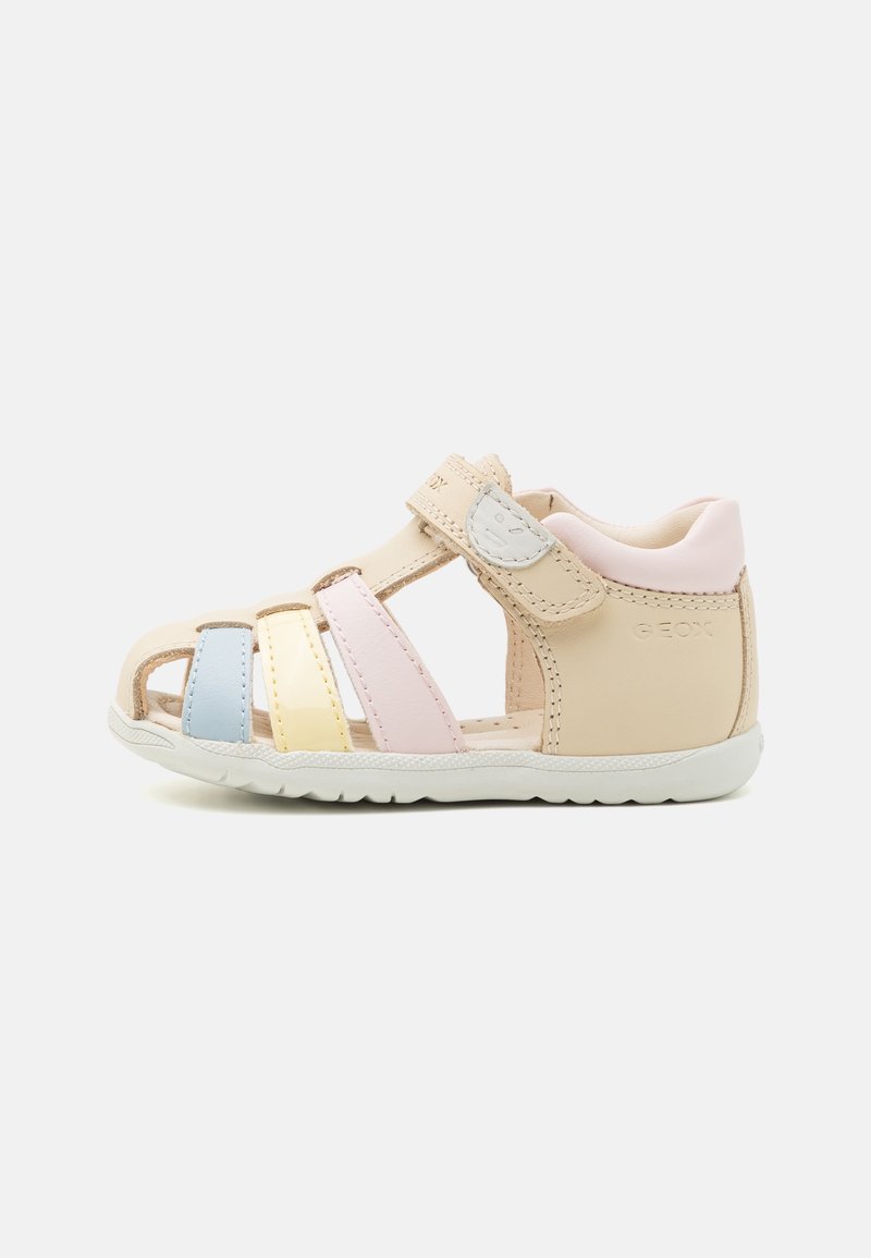 Sandales pour enfants à lanières en beige doux, avec des accents pastel bleu, jaune et rose. Fermeture réglable par Velcro et semelle blanche.