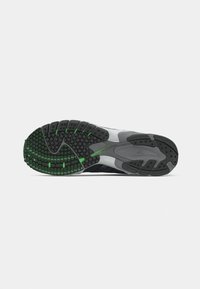 Sneakersåle med en teksturert grå gummibase, som har svarte og grønne traksjonsmønstre og en glatt grå mellomsåle.