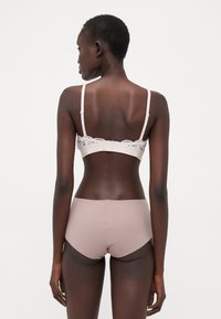 Light pink bra with lace accents, adjustable straps, and matching smooth high-waisted briefs. Soft fabric, seamless design, and minimal detailing.