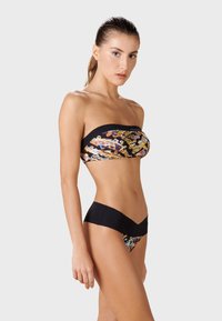 Bikini utan axelband med ett färgglatt abstrakt mönster på toppen och en solid svart rem. Botten har en V-formad svart midjeband och tryck.