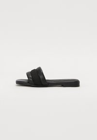 Black slide sandals with two wide straps, one in smooth leather and the other in textured fabric. Flat sole with minimal design.