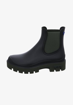 Botín de tobillo negro de goma con un panel elástico verde texturizado, suela gruesa y un acento azul. Cuenta con una etiqueta de la marca en el talón.