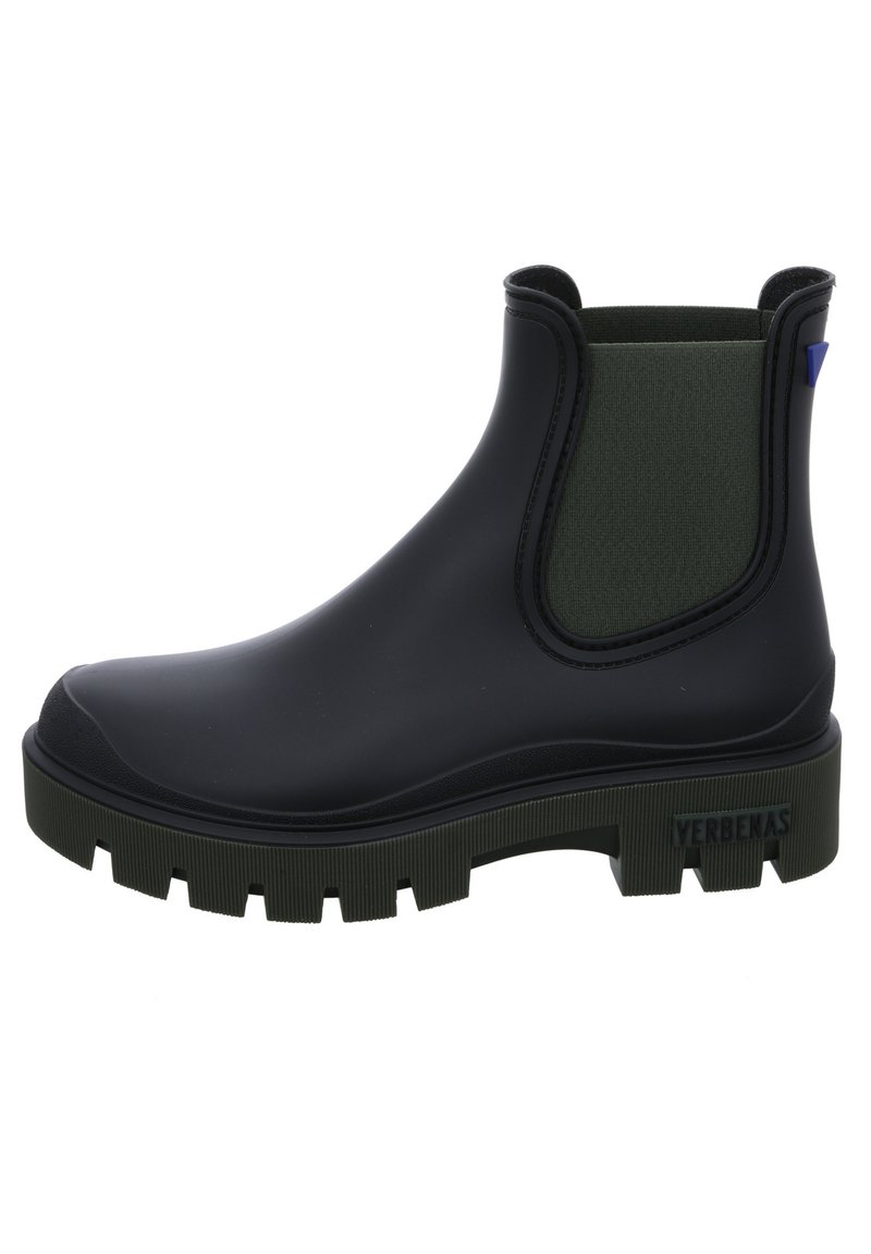 Botín de tobillo negro de goma con un panel elástico verde texturizado, suela gruesa y un acento azul. Cuenta con una etiqueta de la marca en el talón.