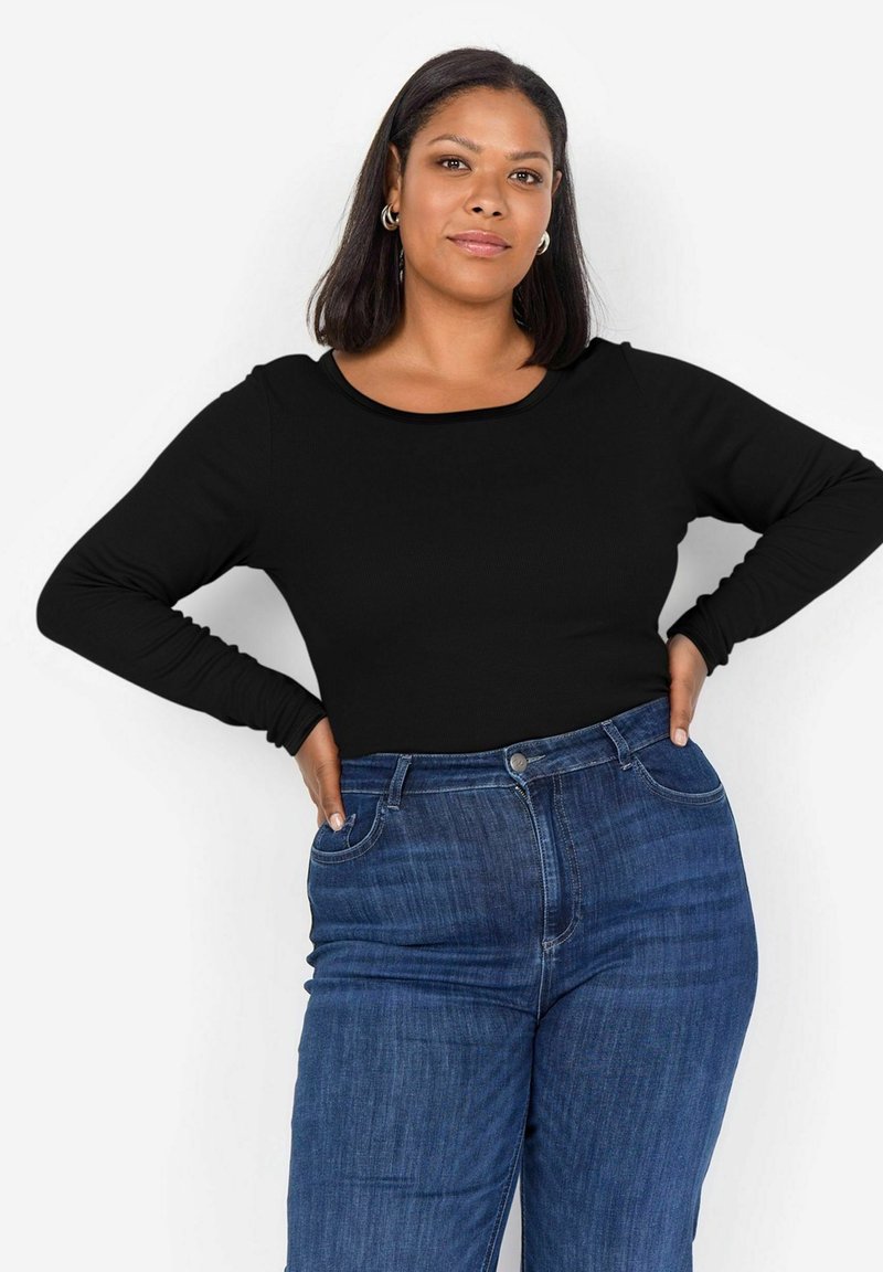 Svart långärmad topp med rundad halsringning, med ribbat mönster, tillsammans med hög midja blå jeans.