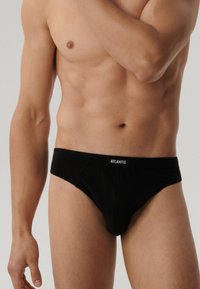 Czarne bawełniane figi bikini z elastycznym paskiem z logo. Posiadają dopasowany kształt i gładką teksturę. Brak dodatkowych wzorów lub akcentów.