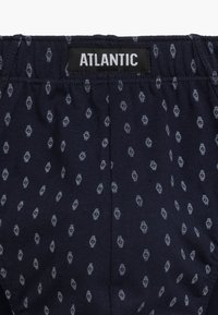Granatowe szorty na elastycznej talii z powtarzającym się jasnoszarym wzorem małych owalnych kształtów. Metka z napisem "ATLANTIC." Gładka bawełniana faktura.
