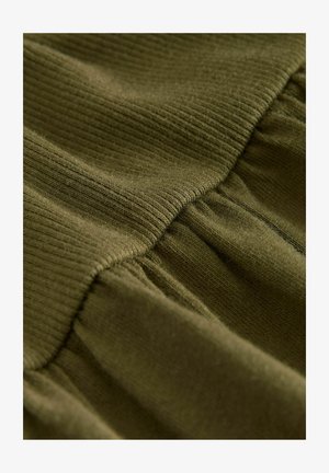 Tejido texturizado de color verde oliva con secciones acanaladas y fruncidas, que muestra una superficie suave, ligeramente difusa y un brillo sutil.