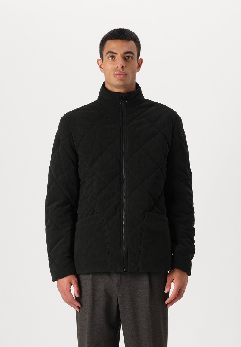 Μαύρο γεμιστό μπουφάν με ψηλό γιακά, μπροστινό φερμουάρ και δύο μεγάλες πλάγιες τσέπες. Κατασκευασμένο από υφασμάτινη ύλη με ζεστή εμφάνιση.