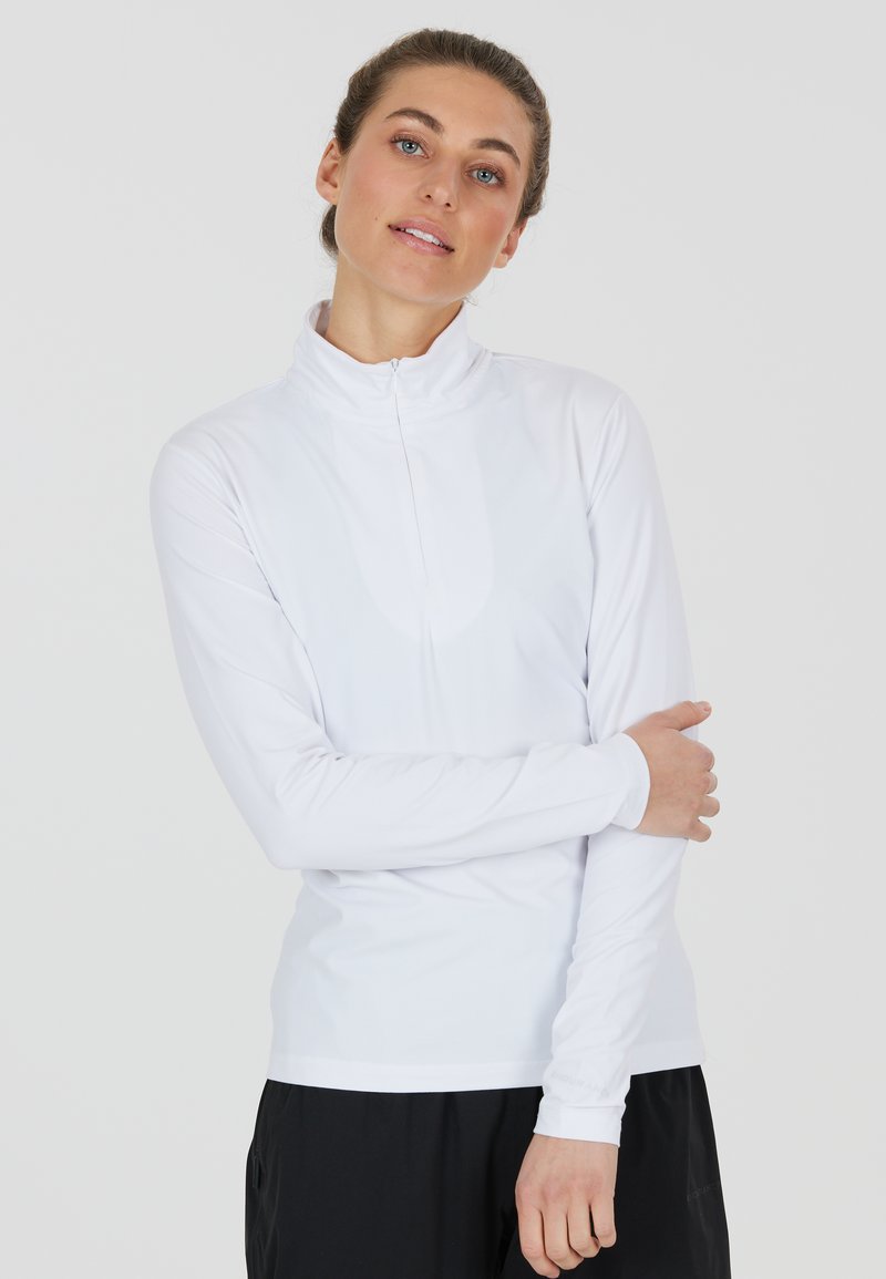 Weißes, langärmeliges Sportoberteil mit hohem Kragen und halbverdecktem Reißverschluss, aus feuchtigkeitstransportierendem Material, enganliegendes Design, glatte Textur.