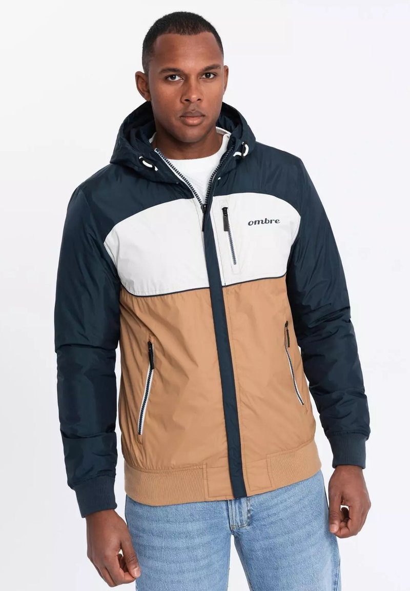 Herren Kapuzenjacke mit Farbblockdesign; marineblau, weiß und tan. Verfügt über Reißverschluss Taschen und elastische Bündchen.