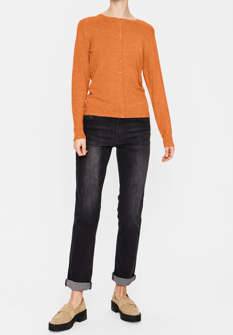 Orangene Knöpfe-Up-Cardigan, lange Ärmel, gerippte Textur, kombiniert mit hochgekrempelten schwarzen Jeans und beigen Loafers. Einfaches Design, keine Muster.