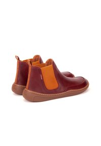 Botas de tobillo de cuero rojo con paneles laterales elásticos naranjas y suela de goma marrón. Textura suave con costuras visibles.