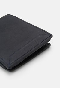 Portefeuille en cuir navy avec une texture lisse, présentant des coutures contrastées et un logo embossé sur le côté. Design compact et pliable.