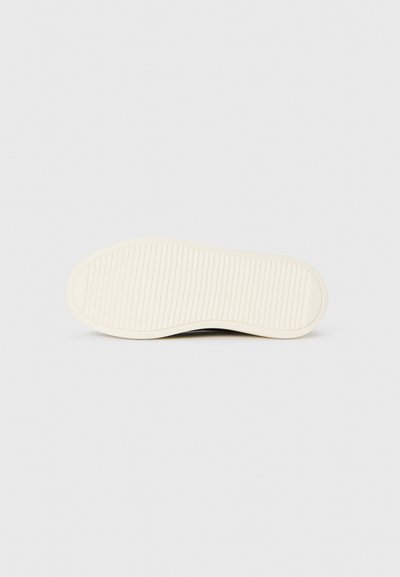 Semelle de chaussure en caoutchouc avec une surface blanche lisse et des rainures horizontales, dotée d'un bout arrondi et d'un profil plat et robuste.