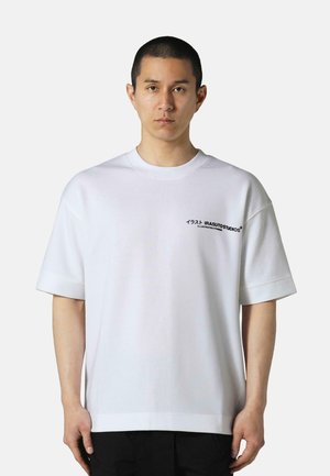 White oversized t-shirt made of cotton with a round neckline. Features "IRASUTOSTUDIOS" text in black on the left chest area.