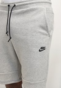 Gray Nike shorts made from cotton blend fabric, featuring an elastic waistband with black drawstrings and a small logo on the left thigh.