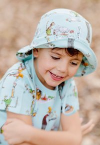 Ljusblå bucket hat med fantasifulla illustrationer av djur och människor; tillverkad av mjukt tyg, med en bred skärm och justerbara remmar.