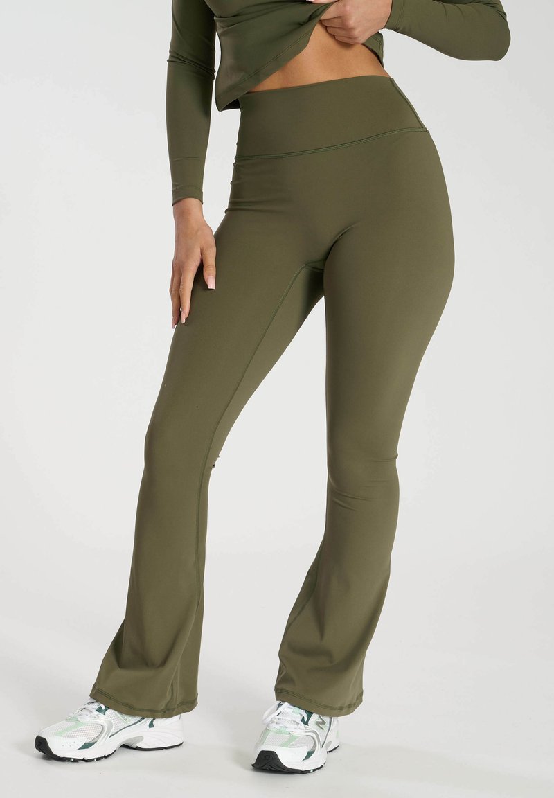 Olivgröna utsvängda leggings i stretchigt tyg med hög midja och sid sömmar. Parat med vita och gröna träningsskor.