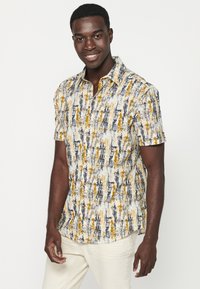 Korte mouw button-up shirt met een gestructureerd, abstract patroon in geel, marineblauw en wit. Kenmerken zijn een kraag en een gebogen zoom.