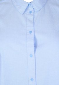 Camicia azzurra chiara con colletto a punta, sei bottoni coordinati e un tessuto liscio e strutturato.