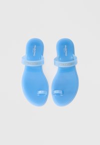 Kék műanyag papucs két pánttal, kábelpántos kialakítással és dombornyomott márkajelzéssel a felső pánton. Simább, fényes felület.