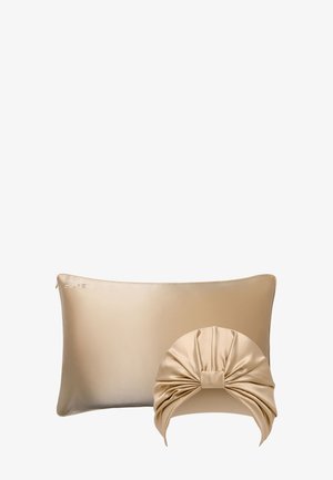 Beige zijden kussensloop met ritssluiting en bijpassende zijden slaapmuts met geplooide strikdetail aan de voorkant.