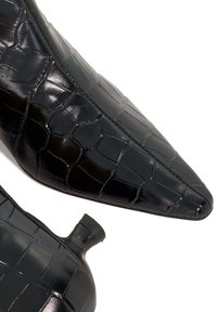 Black pointed-toe heels made of shiny synthetic material with a crocodile texture. Features a small back heel and stitching detail.