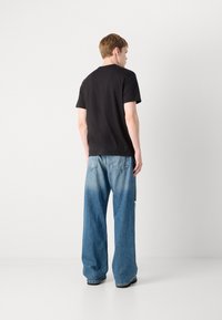 Black cotton t-shirt with a crew neckline, paired with light blue, wide-leg denim jeans featuring a faded texture and back pockets.