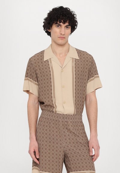 Chemise à manches courtes marron avec un motif et des accents beiges ainsi que des boutons. Shorts assortis, tous deux présentant un design géométrique et une texture de tissu lisse.
