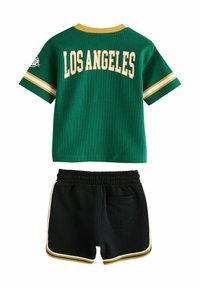Groene mesh trui met "LOS ANGELES" in het geel en dubbele strepen op de mouwen, gecombineerd met zwarte shorts met een zak en contrasterende bies.